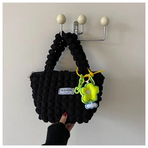 Detail of black bubble textured tote with yellow flower charm and fashion instinct label
