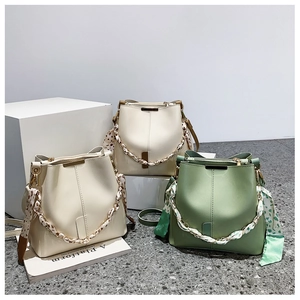 Three textured leather bucket bags with scarf wrapped handles and metal chain detail