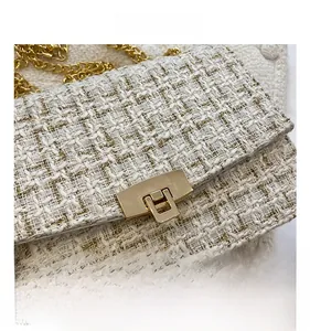 Close-up of beige tweed crossbody bag featuring gold metal swivel lock and chain strap