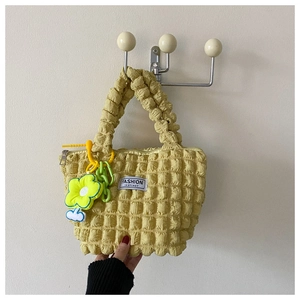Detail of yellow puffy bubble tote bag with fashion tag and floral plush pendant