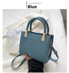 Detail of blue quilted tote bag with woven ring handle and gold hardware accents
