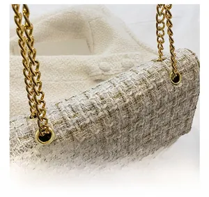 Close-up detail of premium gold metal chain and off-white tweed texture on the bag