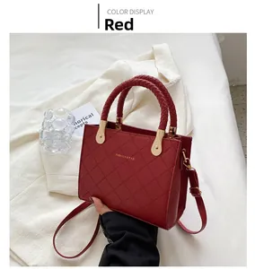 Detail of red quilted faux leather handbag with braided handles and golden hardware