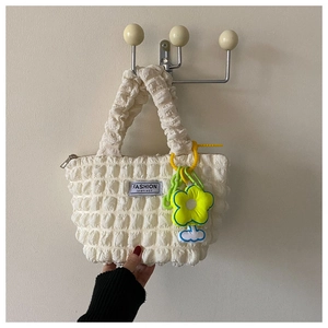 Detail of white bubble texture tote bag with yellow flower and blue cloud charms