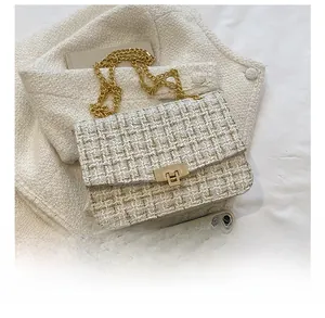 Detail of tweed crossbody bag with golden chain and clasp showing size compared to a phone