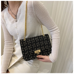 Detail of black gold tweed shoulder bag with metallic clasp and gold chain strap on model