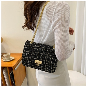 Classic black and white tweed chain bag with gold lock shown in a minimalist home setting