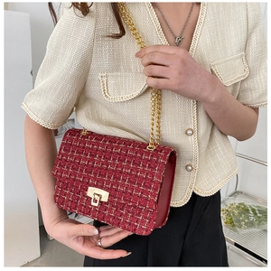 Detail of red tweed shoulder bag with gold chain and woven fabric texture shown on model