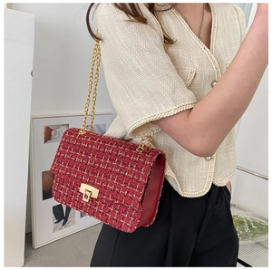 Detail view of red tweed chain bag with gold hardware worn by model in a minimalist setting