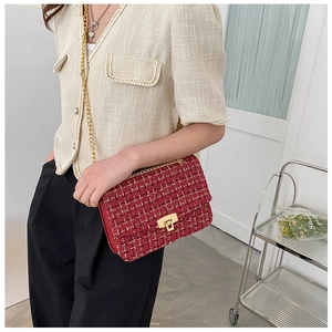 Detail of red tweed shoulder bag featuring golden metallic chain and secure buckle