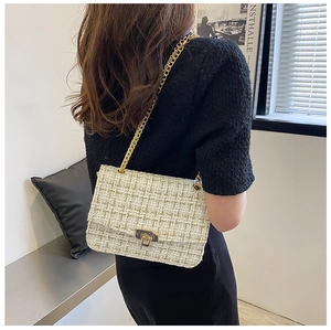 Detail of tweed flap bag with gold chain strap worn by a model in a modern room