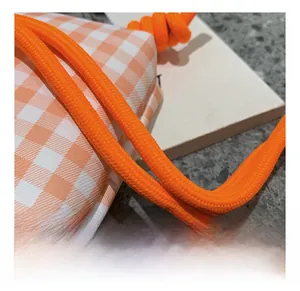 Nahaufnahme des orangefarbenen Seilschultergurts und des orange-weiß karierten Stoffdetails