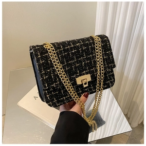 Close-up of black tweed crossbody bag with gold chain and elegant metal swivel lock