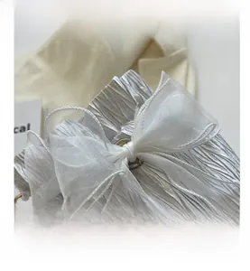 Detailed close-up of metallic pleated fabric bucket bag with a large organza bow