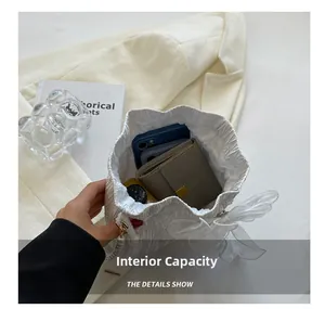 Interior detail of white pleated bucket bag showing large capacity for phone and wallet