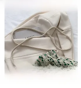 Detail of woven drawstring bucket bag with beige and green textures and matching strap
