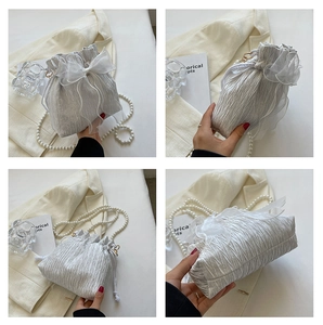 Detail view of silver pleated bucket bag featuring pearl strap and mesh bow accent