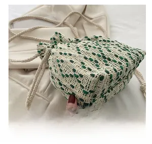 Detail view of woven drawstring bucket bag showing green and beige textured pattern
