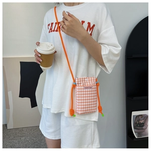 Detailansicht einer orangefarbenen karierten Canvas-Handytasche mit Kordelgurt am Modell