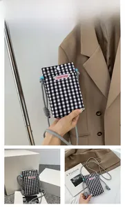 Detailansicht einer schwarz-karierten Handy-Stofftasche mit Knopf und Kordelgurt