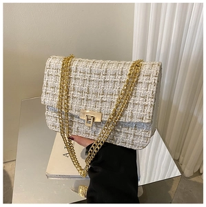 Close-up of white tweed chain bag with gold metal turn-lock and woven texture detail