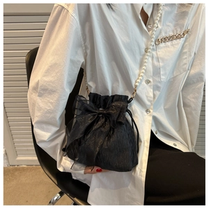 Close-up of black pleated bucket bag with tulle bow and pearl chain strap details