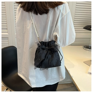 Detail of black pleated bucket bag with large organza bow and pearl chain strap