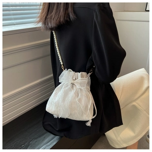 Detail of white pleated bucket bag with large organza bow and pearl chain strap
