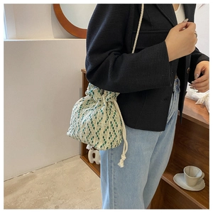Detail of green and beige checkered woven drawstring bucket bag with a soft texture