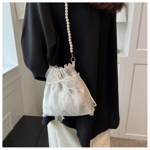 Detail of white pleated bucket bag with pearl chain strap and organza bow accent