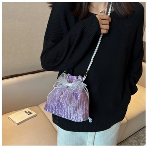 Detail of purple ruched bucket bag with organza bow and pearl shoulder strap
