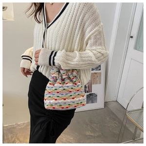 Detailed close-up of colorful crochet knit bucket bag with drawstring closure and texture