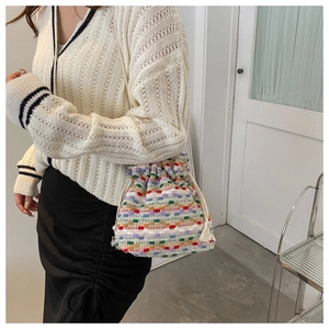 Detail of colorful knitted bucket bag showing striped crochet texture and drawstring tassel
