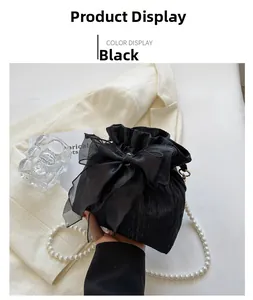 Detail of black drawstring bucket bag with mesh bow and elegant pearl shoulder strap