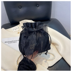 Detail of black pleated bucket bag with sheer organza bow and sparkling glitter accents