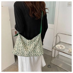 Detail showing high-capacity woven shoulder bag in green and white with wide strap