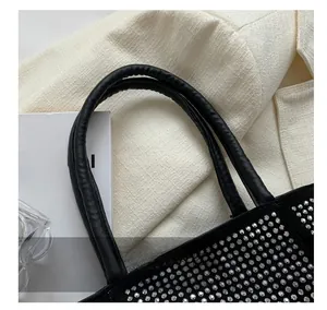 Detail of comfortable round leather handle on a stylish black bucket bag with rhinestones