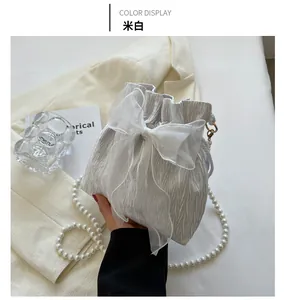 Detail of off-white pleated bucket bag with large organza bow and pearl strap