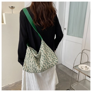 Model wearing a large tweed tote bag with green polka dots and a bright green shoulder strap