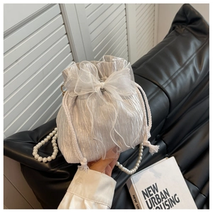 Detail of silver pleated bucket bag with drawstring closure and elegant pearl strap