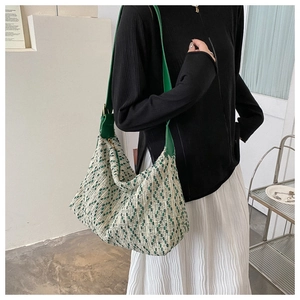 Detail of green woven tote bag showing vertical knit texture and wide leather shoulder strap