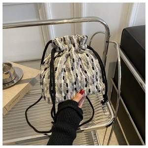 Detail of tweed bucket bag with drawstring closure on a silver trolley in modern setting