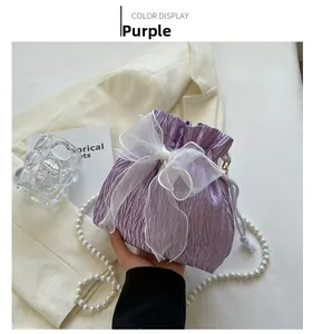 Detailed shot of purple drawstring bucket bag with organza bow and pearl handle