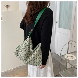 Detailed view of woven tote bag with vibrant green strap on model in modern room