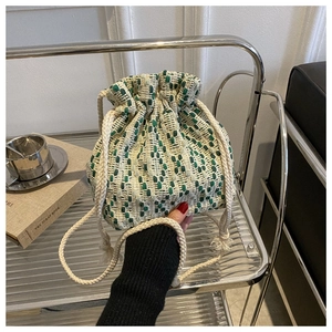 Detail of green and white woven bucket bag with thick cotton drawstring closure