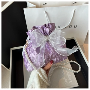 Detail of lavender drawstring bucket bag featuring large organza bow and pearl chain strap