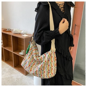 Detail of woven tote bag with colorful polka dots and green leaf charm on a wide strap