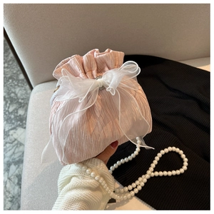 Detailed view of pink pleated bucket bag with organza bow and pearl shoulder chain