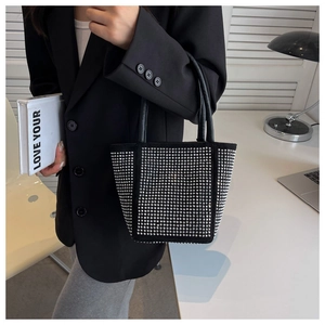 Detail of black tote bag featuring silver stud rivets and premium leather handle