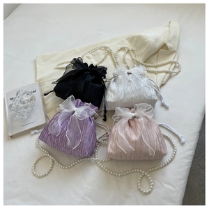 Detail of four colorful drawstring bucket bags with large organza bows and pearl straps